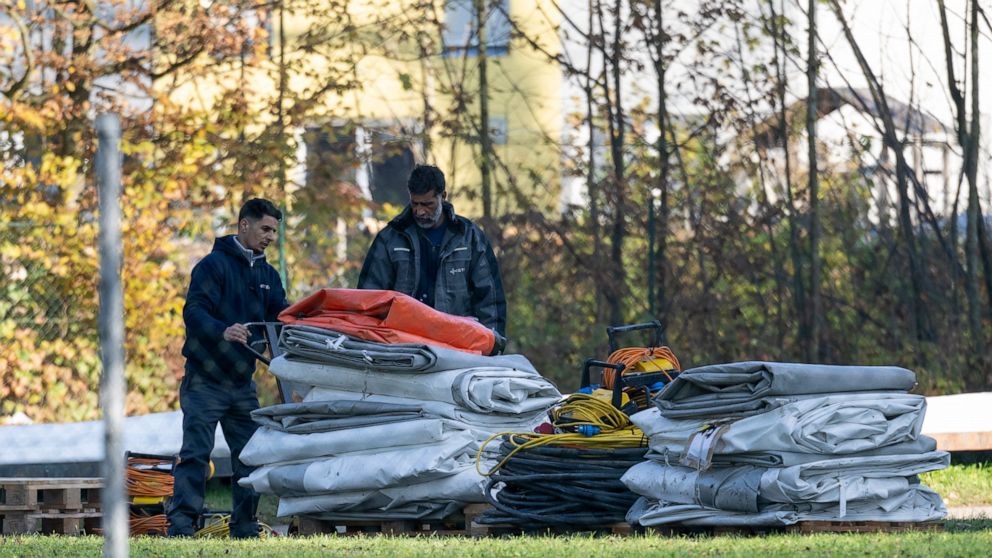 Two men dismantle tents tents that were set up as shelters for refugees in St. Georgen im Attergau, Austria, Monday, Nov. 14, 2022. In a weeks-long standoff with the Austrian government over the accommodation of rising numbers of asylum seekers in th