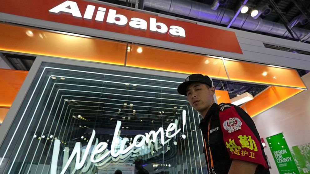 A security guard passes by the Alibaba booth at a trade show in Beijing, China, Tuesday, Sept. 7, 2021. Companies in China would need government approval to transfer important data abroad under proposed rules announced Friday that would tighten Beiji