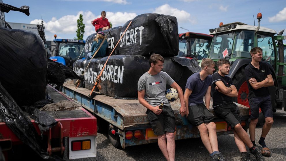FILE- Protesting farmers talk at a blockade outside a distribution center for supermarket chain Aldi in the town of Drachten, northern Netherlands, Monday, July 4, 2022. Representatives of Dutch farmers were meeting Friday, Aug. 5, 2022 with Prime Mi