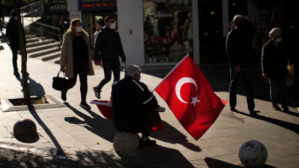 A man sells Turkish flags in a commercial area in Kadikoy neighbourhood in Istanbul, Turkey, Thursday, Dec. 2, 2021. Turkey’s beleaguered currency has been plunging to all-time lows against the U.S. dollar and the euro in recent months as President R