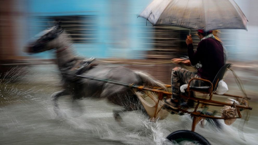 A horse pulls a buggy with passengers through a street flooded by heavy rains, in Havana, Cuba, Friday, June 3, 2022. Heavy rains have drenched Cuba with almost non-stop rain for the last 24 hours as tropical storm watches were posted Thursday for Fl