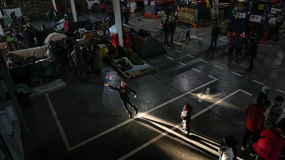 A migrant boy plays with a ball in a ray of sunshine at the "Bruzgi" checkpoint logistics center at the Belarus-Poland border near Grodno, Belarus, Wednesday, Dec. 22, 2021. Since Nov. 8, a large group of migrants, mostly Iraqi Kurds, has been strand