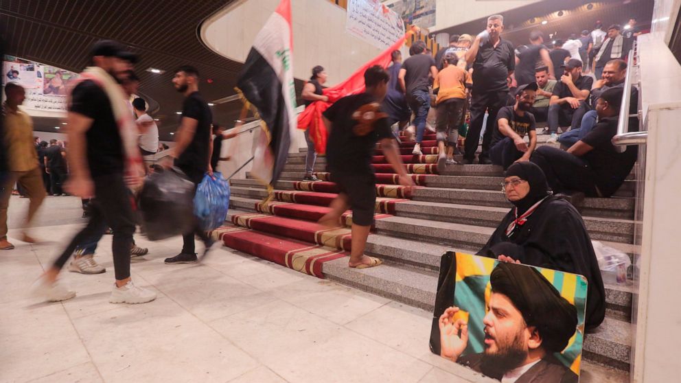 Followers of Shiite cleric Muqtada al-Sadr hold posters with his photo during a sit-in, inside the parliament in Baghdad, Iraq, Wednesday, Aug. 3, 2022. The Influential Shiite cleric has told his followers to continue their sit-in inside Iraq’s gover