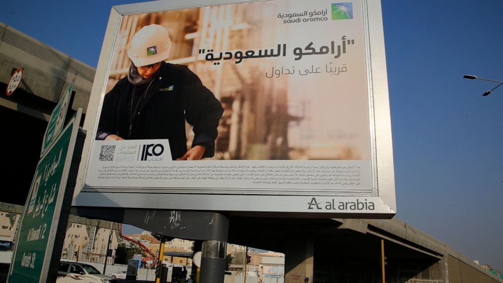FILE - A man walks under a billboard displaying an advertisement for Saudi Arabia's state-owned oil giant Aramco with Arabic reading "Saudi Aramco, soon on stock exchange" in Jiddah, Saudi Arabia on Nov. 12, 2019. Oil giant Saudi Aramco said Sunday, 