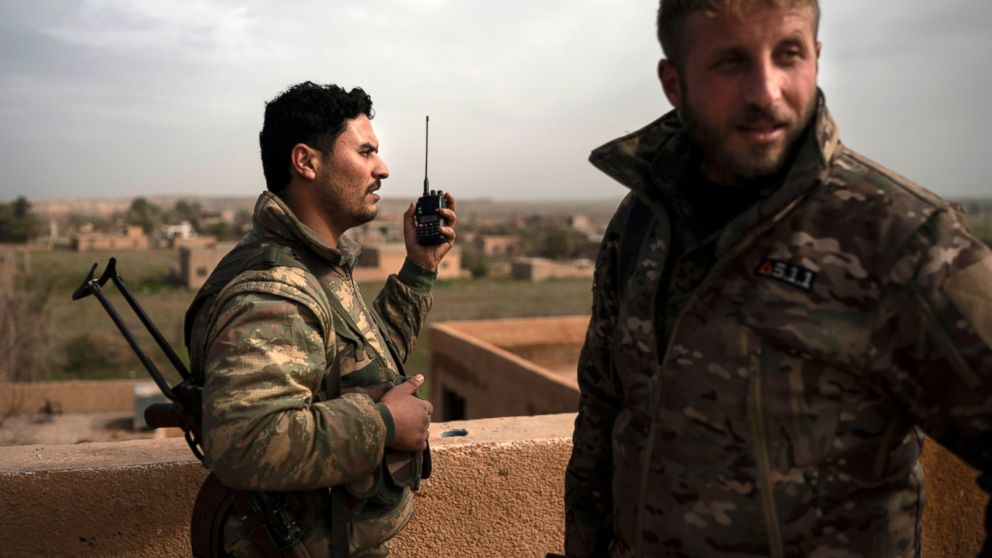 U.S.-backed Syrian Democratic Forces (SDF) fighters talk on a radio in a rooftop position as fight against Islamic State militants continues in the village of Baghouz, Syria, Saturday, Feb. 16, 2019. (AP Photo/Felipe Dana)