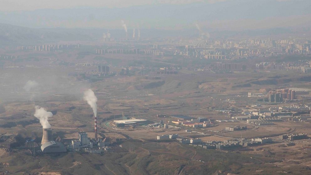 FILE - Smoke and steam rise from towers at the coal-fired Urumqi Thermal Power Plant as seen from a plane in Urumqi in western China's Xinjiang Uyghur Autonomous Region on April 21, 2021. China is promoting coal-fired power as the ruling Communist Pa
