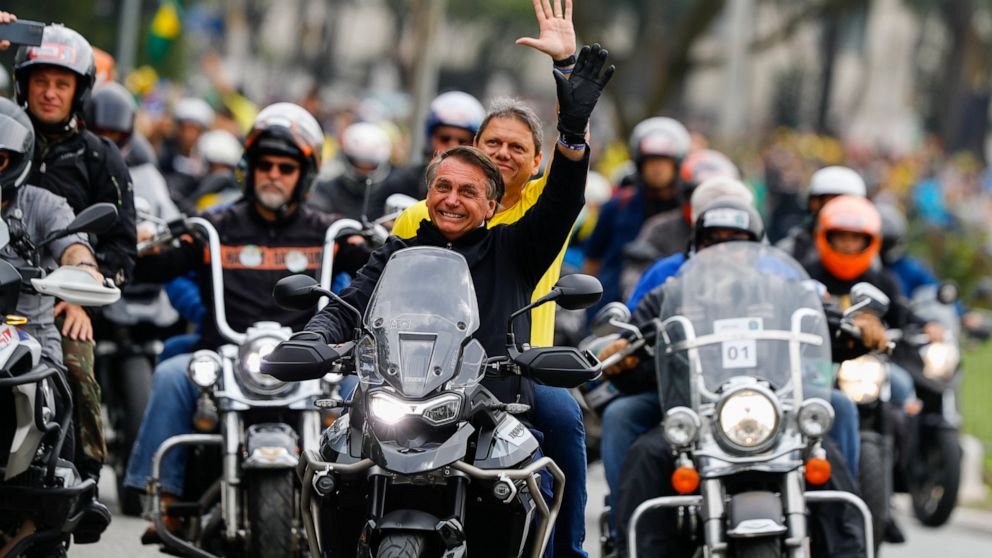 Brazil's President Jair Bolsonaro who is running for re-election, leads a caravan of motorcycle enthusiasts with Sao Paulo governor's candidate Tarcisio de Freitas, riding on the backseat, during a campaign event in Sao Paulo, Brazil, Saturday, Octob
