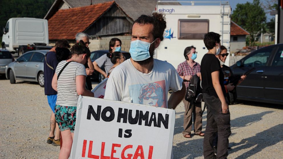 A man holds a banner during a protest against the violent pushbacks of migrants, allegedly conducted by Croatian police, near the border crossing between Croatia and Bosnia Herzegovina in Maljevac, Croatia, Saturday, June 19, 2021. More than one hund