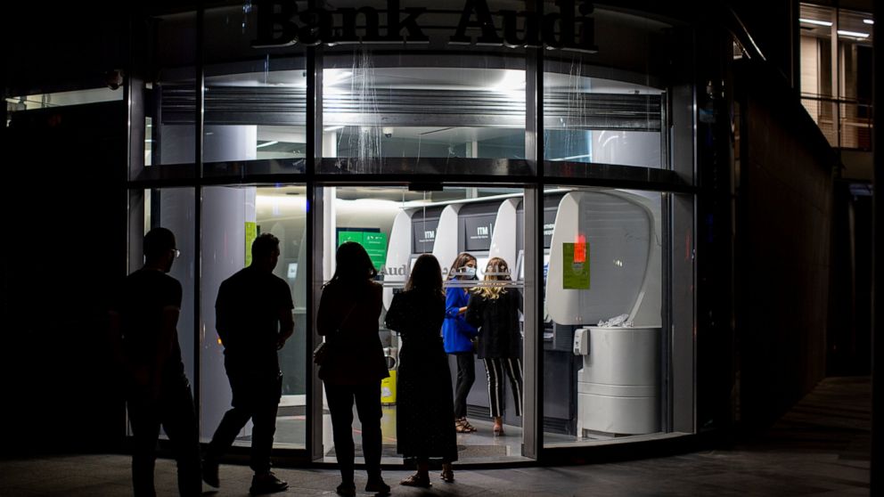 FILE - In this June 2, 2021, file photo, clients wait to use ATM machines outside a closed bank in Beirut, Lebanon. Lebanon’s local currency hit a new record low on Sunday, June 13, 2021, with the country's economic and political crisis worsening wit
