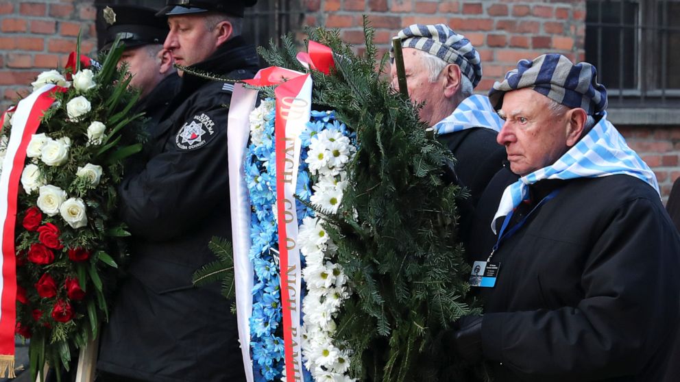 Survivors carry a wreath at the Auschwitz Nazi death camp in Oswiecim, Poland, Monday, Jan. 27, 2020. Survivors of the Auschwitz-Birkenau death camp gathered for commemorations marking the 75th anniversary of the Soviet army's liberation of the camp,