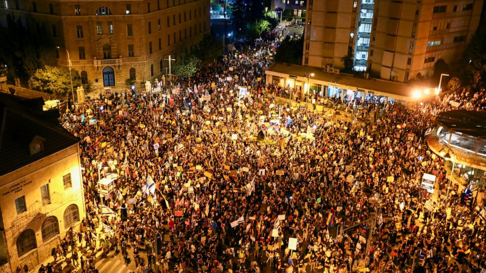 Thousands of protesters chant slogans and hold signs during a protest against Israel's Prime Minister Benjamin Netanyahu outside his residence in Jerusalem, Saturday, Aug 1, 2020. Protesters demanded that the embattled Israeli leader to resign as he 