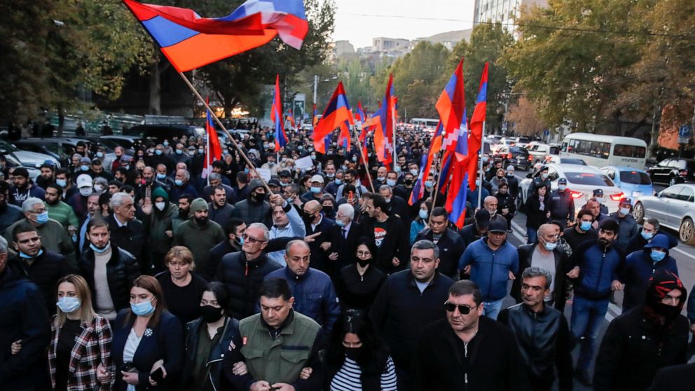 Protesters with Armenian flags walk along a street during a protest against an agreement to halt fighting over the Nagorno-Karabakh region, in Yerevan, Armenia, Thursday, Nov. 12, 2020. Thousands of people flooded the streets of Yerevan once again on