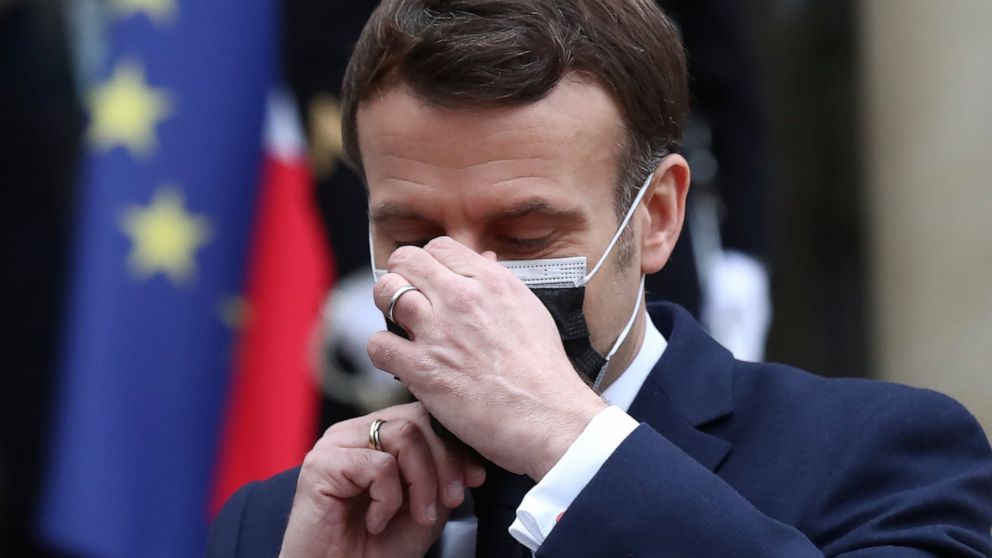 French President Emmanuel Macron takes off his face mask as he welcomes Serbian President Aleksandar Vucic for a working lunch at the Elysee Palace in Paris, Monday, Feb. 1, 2021. Serbian President Aleksandar Vucic is in Paris for bilateral talks wit
