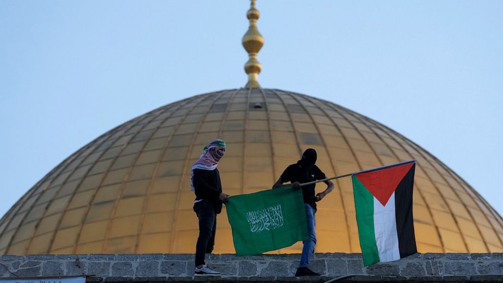 FILE - Masked Palestinians carry Palestinian and Hamas flags during Eid al-Fitr celebrations next to the next to the Dome of the Rock Mosque in the Al-Aqsa Mosque compound in the Old City of Jerusalem, May 2, 2022. The Palestinian militant group Hama