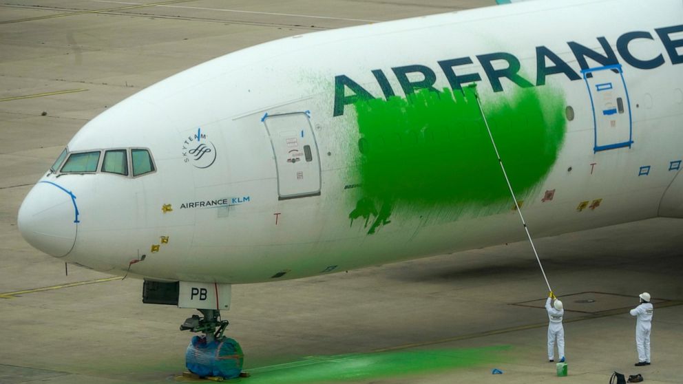 In this photo provided by Greenpeace, Greenpeace activists paint a side of an Air France Boeing 777, which was parked without passengers, Friday March 5, 2021 at Roissy airport, north of Paris. Nine Greenpeace activists were arrested after vandalizin