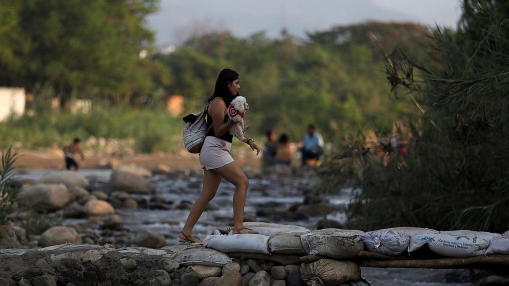 A woman holding her pet crosses illegally into Colombia near the Simon Bolivar International Bridge in La Parada near Cucuta, Colombia, Wednesday, May 1, 2019, on the border with Venezuela. The border area near Cucuta was peaceful Wednesday, even as 