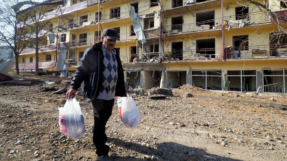 Vovik Zakharian, 72, walks past his apartment building damaged by shelling by Azerbaijan's forces during a military conflict in Shushi, outside Stepanakert, the separatist region of Nagorno-Karabakh, Thursday, Oct. 29, 2020. Fighting over the separat