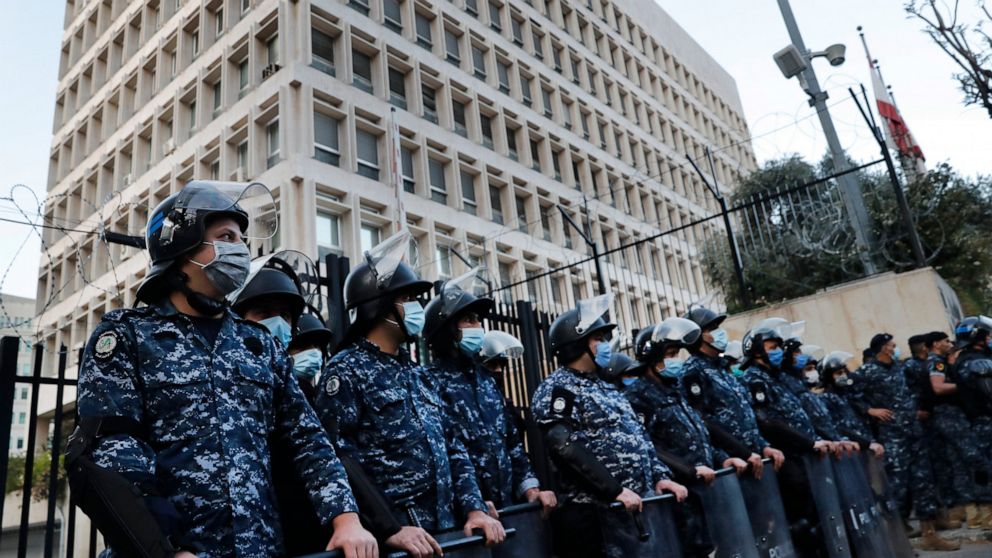 Lebanese riot police wear masks to help curb the spread of the coronavirus, as they stand guard in front the central bank building, where the anti-government protesters protest against the Lebanese central bank's governor Riad Salameh and against the