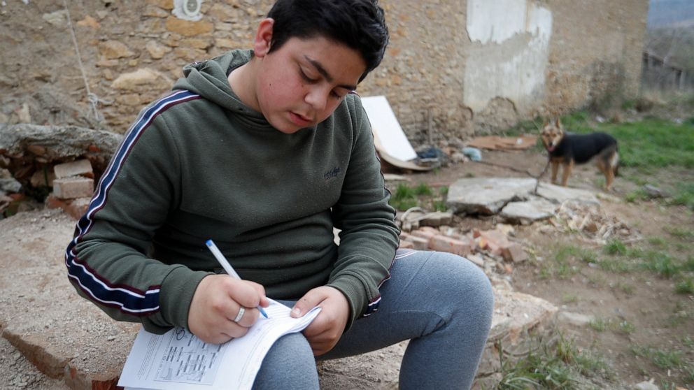 Mihaly Kovacs, a 12 year-old Hungarian boy, works on his homework outside his home in Bodvaszilas, Hungary, Monday, April 12,2021. Many students from Hungary's Roma minority do not have access to computers or the internet and are struggling to keep u