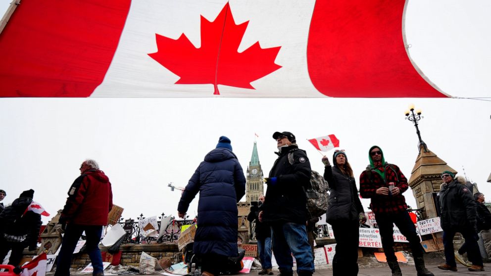 A Canada flag is hung between traffic light posts in front of Parliament Hill during a protest against COVID-19 restrictions in Ottawa, on Friday, Feb. 11, 2022. Ontario’s premier declared a state of emergency Friday in reaction to the truck blockade