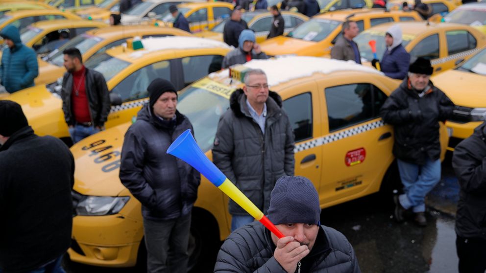 FILE - In this Wednesday, Feb. 13, 2019, file photo a taxi driver blows into a horn during a protest against ride hailing services in Bucharest, Romania. The Romanian government has issued an emergency decree ramping up steep fines for drivers of rid