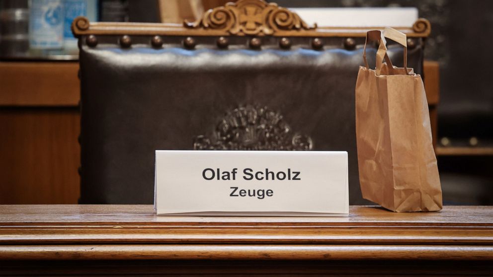 A plastic sign with the text 'Olaf Scholz witness' stands in front of a seat on the Senate bench before the start of a meeting of the parliamentary investigation committee in Hamburg, Germany, Friday, Aug. 19, 2022. German Chancellor Olaf Scholz is d