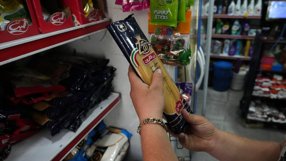 A man looks at a pack of pasta at a grocery store in Tehran, Iran, Wednesday, May 11, 2022. Iran abruptly raised prices as much as 300% for a variety of staples such as cooking oil, chicken, eggs and milk on Thursday. (AP Photo/Vahid Salemi)