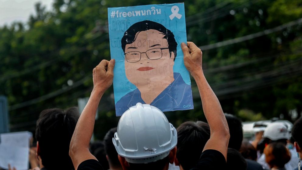 A pro-democracy activist displays a poster featuring an image of recently detained protest leader Parit Chiwarak during a demonstration at Kaset intersection, suburbs of Bangkok, Thailand, Monday, Oct. 19, 2020. Thailand's embattled Prime Minister Pr