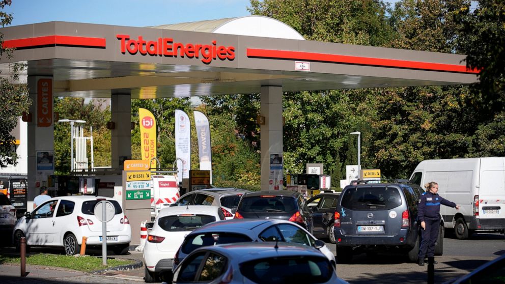 A police officer directs cars as drivers line up in a gas station in Paris, Tuesday, Oct.11, 2022. Shortages which the government says are largely caused by strikes that have hit French fuel refineries are making life difficult for drivers in the Par