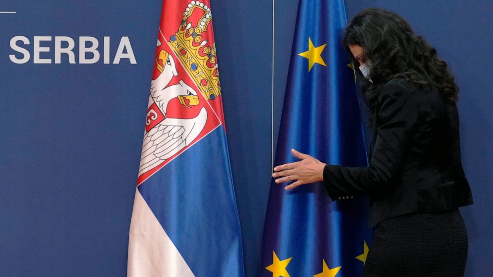 FILE - A protocol staff member adjusts a EU flag next to a Serbian flag, prior to the press conference of Montenegro's Prime Minister Zdravko Krivokapic and his Serbian counterpart Ana Brnabic at the Serbia Palace in Belgrade, Serbia, Wednesday, Nov.