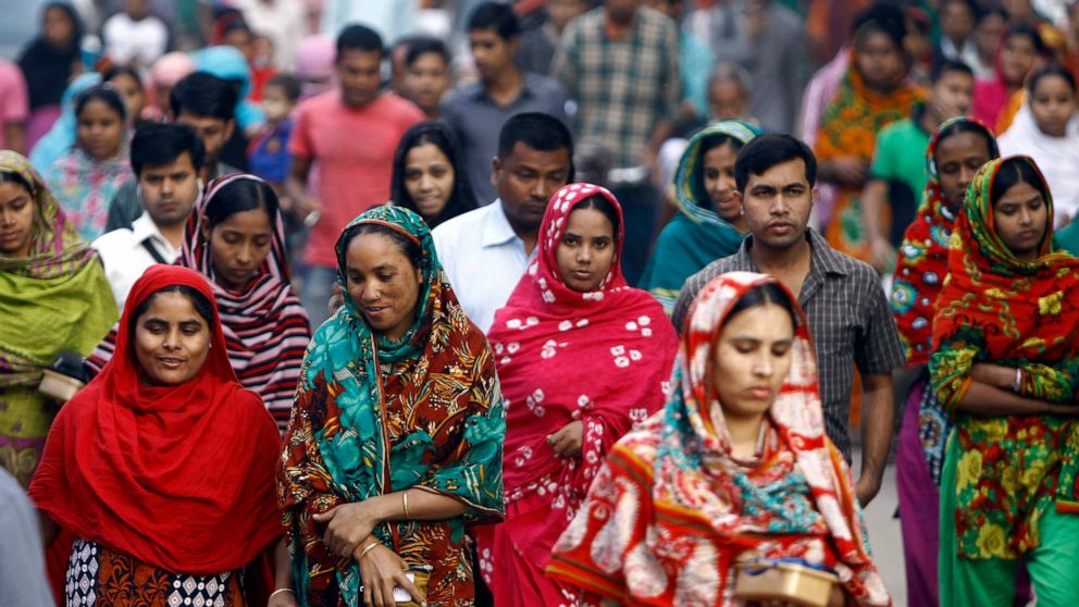 FILE - In this Feb. 13, 2014 file photo, Bangladeshi garment workers arrive for work early morning in Dhaka, Bangladesh. A survey of factory owners in Bangladesh has found that major fashion retailers that are closing shops and laying off workers in 