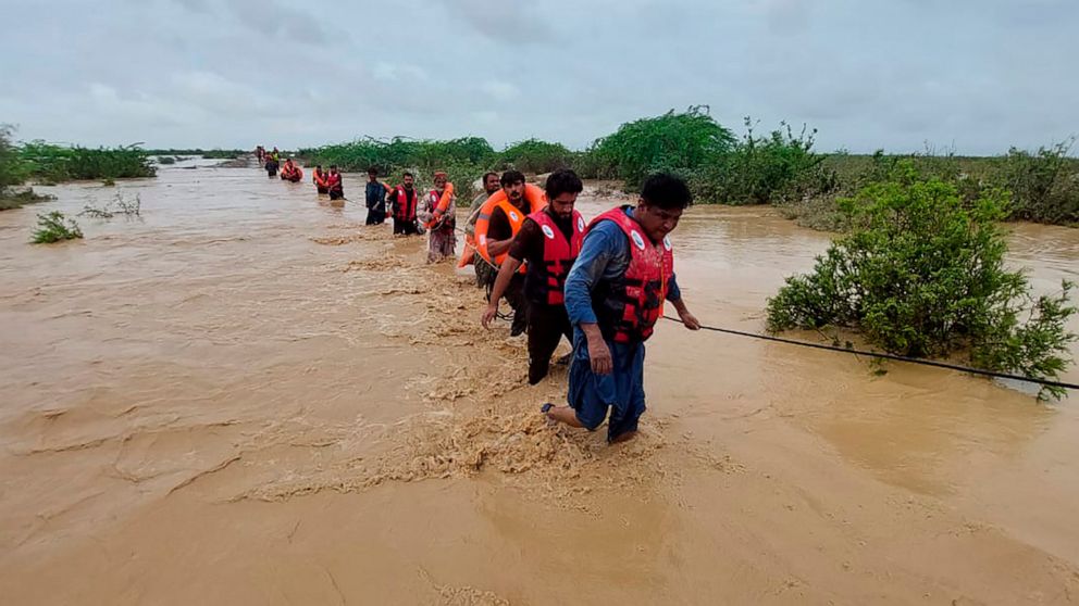 Rescue workers help villagers to evacuate them from flooded area caused by heavy rains, in Lasbella, a district in Pakistan's southwest Baluchistan province, Tuesday, July 26, 2022. Officials say on Wednesday, rescuers backed by troops are using boat