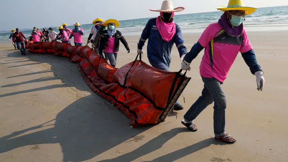 Workers drag an oil spill boom out onto Mae Ram Phueng Beach in hopes of containing any oil washing ashore from a recent spill off the coast of Rayong, eastern Thailand, Friday, Jan. 28, 2022. An oil slick off the coast of Thailand continued to expan