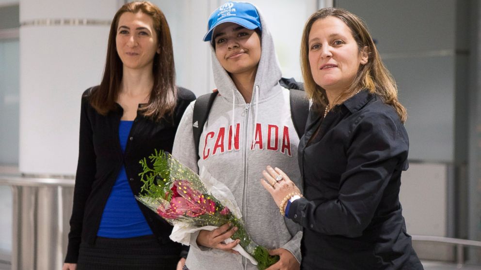 Rahaf Mohammed Alqunun, 18, center, stands with Canadian Minister of Foreign Affairs Chrystia Freeland, right, as she arrives at Toronto Pearson International Airport, on Saturday, Jan.12, 2019. The Saudi teen fled her family while visiting Kuwait an