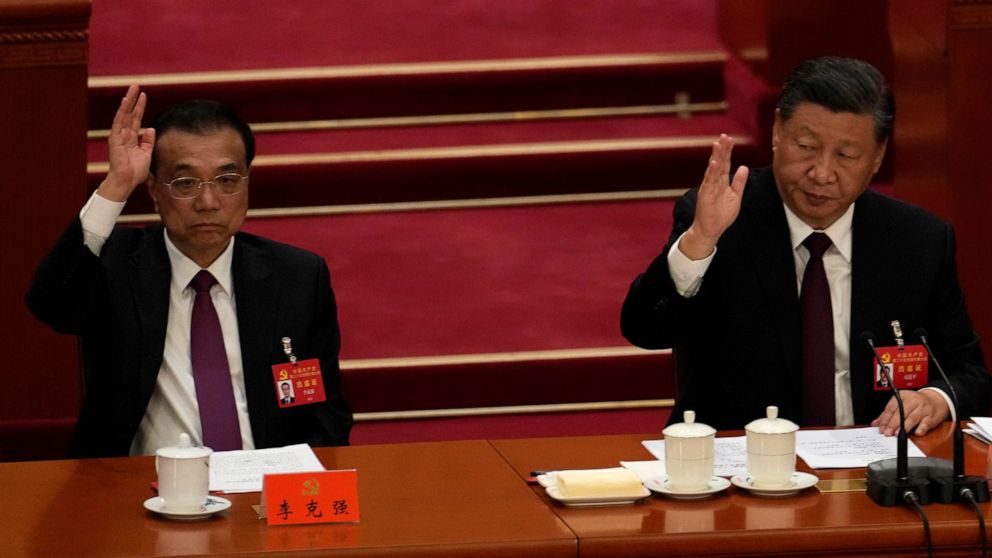 Chinese President Xi Jinping looks over as Chinese Premier Li Keqiang raises his hand to vote at the closing ceremony of the 20th National Congress of China's ruling Communist Party at the Great Hall of the People in Beijing, Saturday, Oct. 22, 2022.