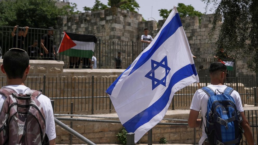 Palestinians and Israelis wave their national flags outside Jerusalem's Old City as Israelis mark Jerusalem Day, an Israeli holiday celebrating the capture of the Old City during the 1967 Mideast war. Sunday, May 29, 2022. Israel claims all of Jerusa