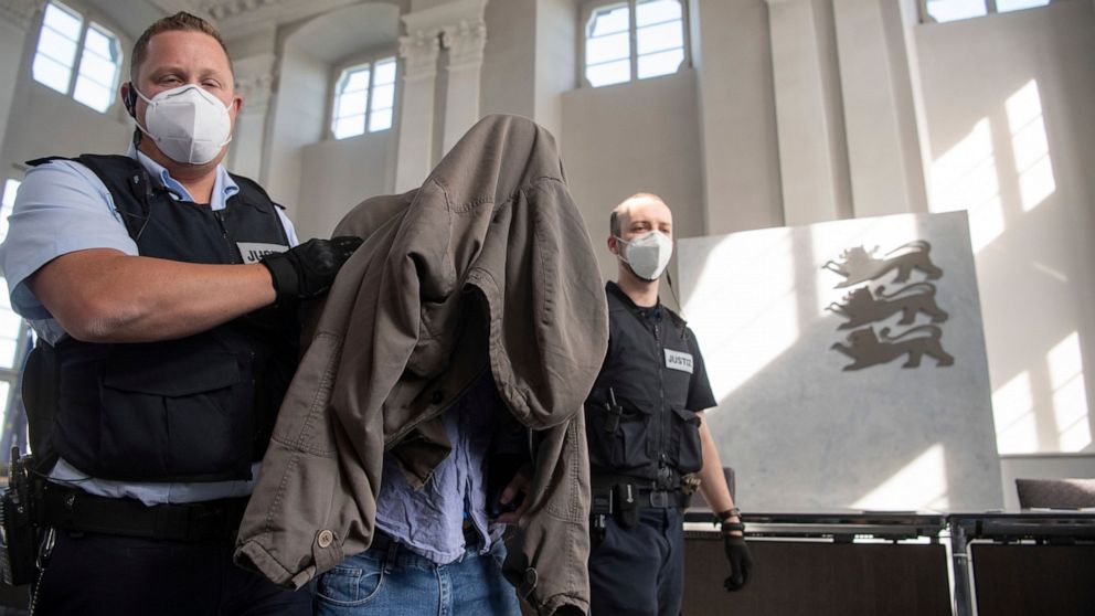 The accused in the trial of a six-time murder in Rot am See is led to his seat in a hall of the regional court in Ellwangen, Germany, Friday, July 10, 2020. The young man is said to have killed his parents, two half-brothers and sisters as well as hi