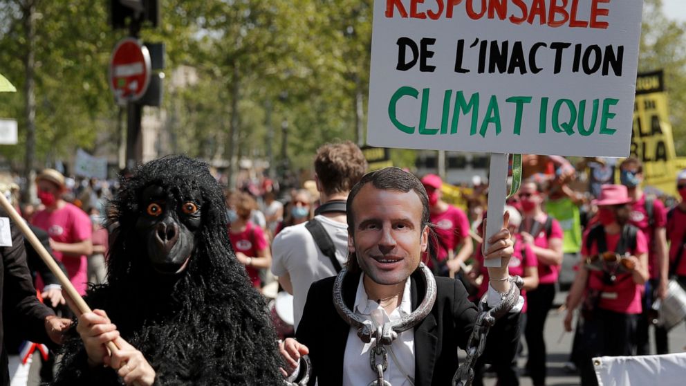 A protester wearing a mask depicting French President Emmanuel Macron holds a bord reading « Liable for climate inaction » during a rally against the climate change in Paris, Sunday, May 9, 2021. Thousands of French demonstrators took to the streets 