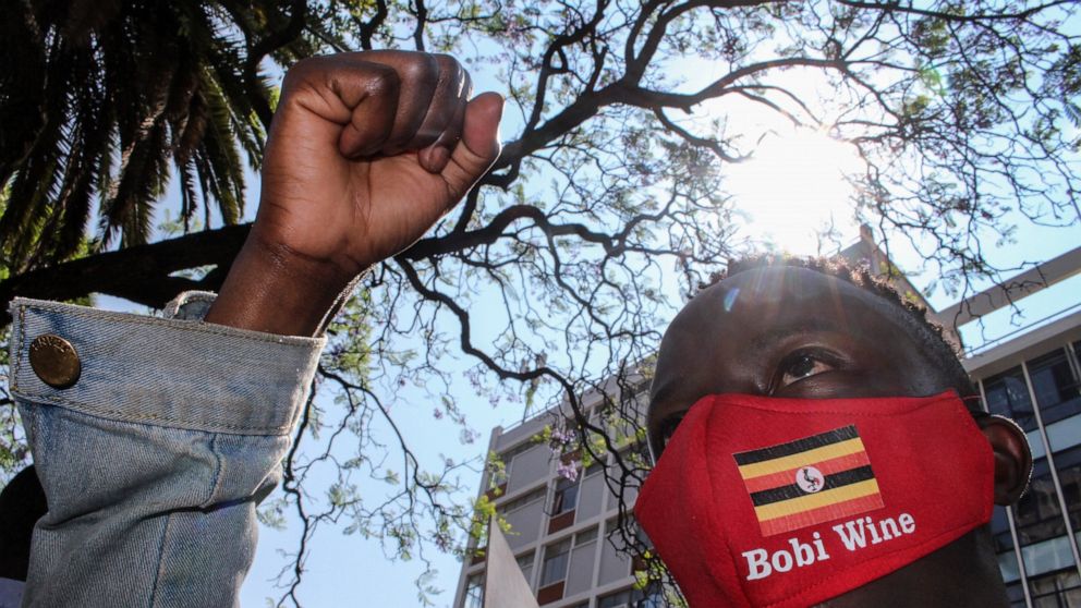A Ugandan supporter of opposition presidential candidate Bobi Wine, wearing a face mask with the Ugandan national flag, joins others to protest his arrest and call for his release and an end to police brutality, outside the Ugandan High Commission in