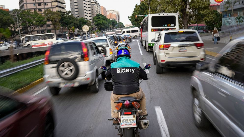 A Ridery app employee makes his way through traffic to pick up a customer, in Caracas, Venezuela, Wednesday, May 11, 2022. Ridery is one of at least three Venezuelan ride-sharing apps that launched during the pandemic — and which have taken advantage