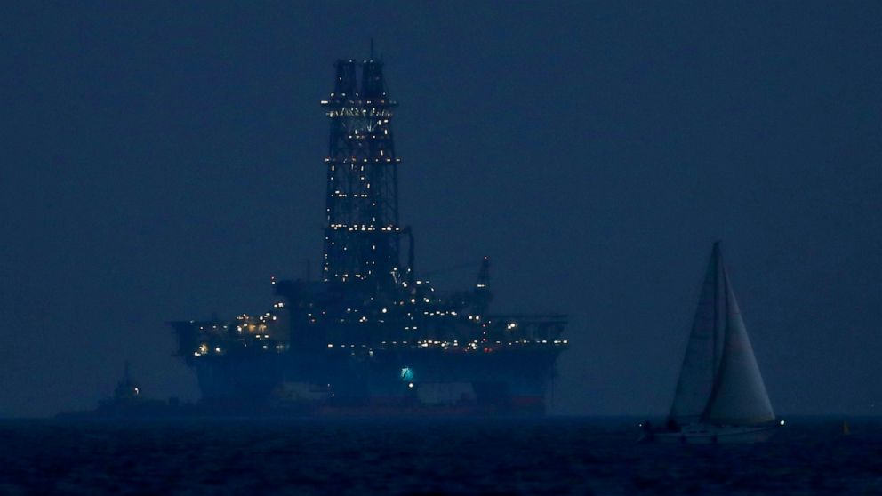 FILE - An offshore drilling rig is seen in the waters off Cyprus' coastal city of Limassol, July 5, 2020, as a sailboat sails in the foreground. A new gas discovery off Cyprus' southern coast that's estimated to contain around 2.5 trillion cubic feet