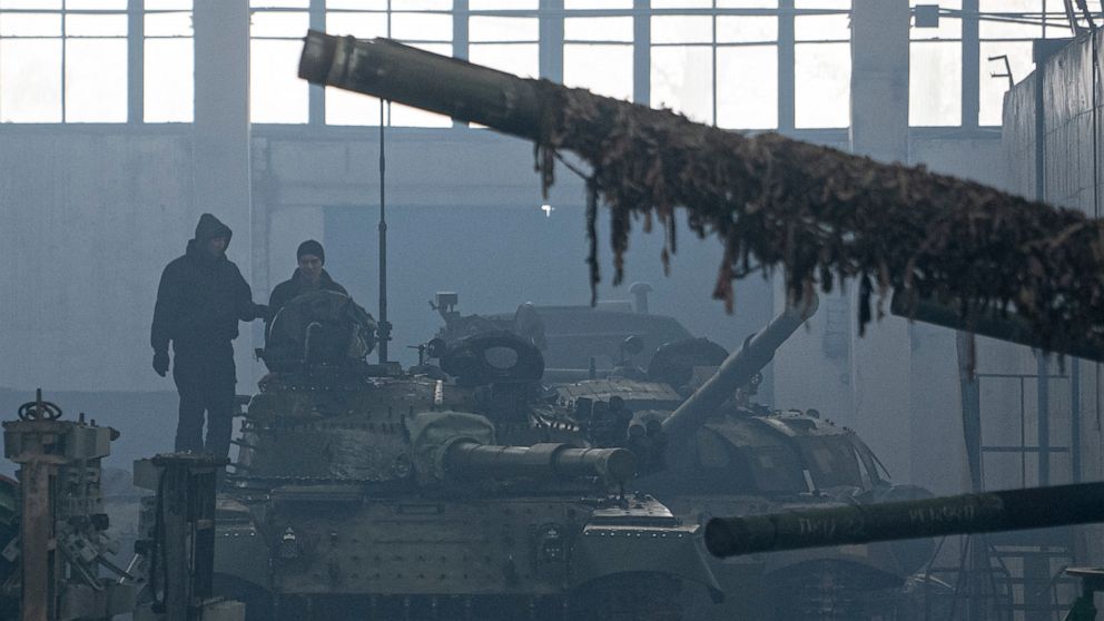 Workers stand atop a tank T-64 on Repair Tank Factory in Kharkiv, Ukraine, Monday, Jan. 31, 2022. The situation in Kharkiv, just 40 kilometers (25 miles) from some of the tens of thousands of Russian troops massed at the border of Ukraine, feels part