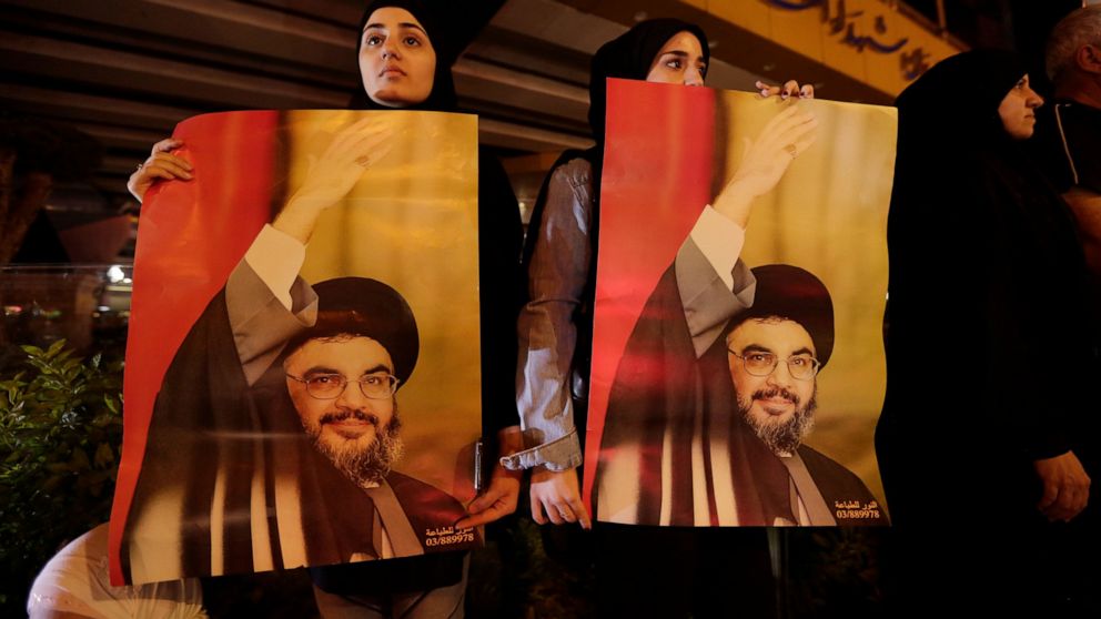 FILE - In this Oct. 25, 2019 file photo, supporters of Hezbollah leader Sayyed Hassan Nasrallah hold his picture, in the southern suburbs of Beirut, Lebanon. Nasrallah has thrown his support behind the Lebanese government seeking financial assistance