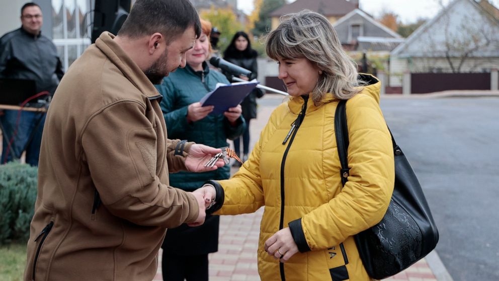 Acting Head of the Donetsk People's Republic Denis Pushilin hands over the keys to a new apartment to a woman, a resident in Cheryomushki district, in Mariupol, Donetsk People's Republic, Ukraine, Friday, Nov. 4, 2022. (AP Photo/Alexei Alexandrov)