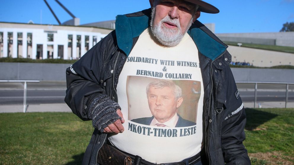 Demonstrator Dierk von Behrens protests outside Parliament House in Canberra, Australia, Thursday, June 17, 2021 against the prosecution of lawyer Bernard Collaery whose picture is on the demonstrator's shirt. Critics of the secret prosecutions of a 
