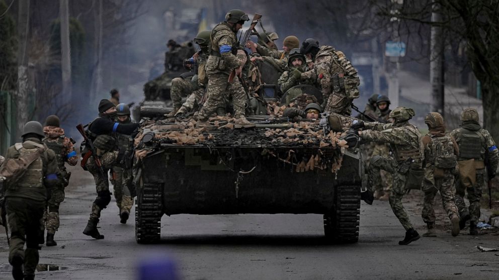 Ukrainian servicemen climb on a fighting vehicle outside Kyiv, Ukraine, Saturday, April 2, 2022. As Russian forces pull back from Ukraine's capital region, retreating troops are creating a "catastrophic" situation for civilians by leaving mines aroun