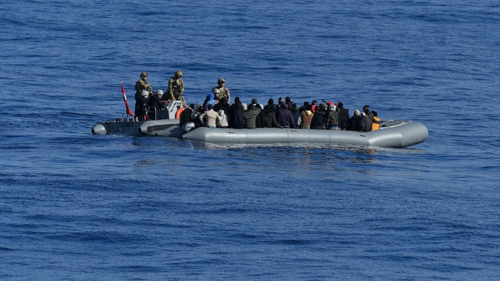 In this image provided by the Turkish Military, members of Turkish forces, left, approach migrants aboard a dinghy in the mid Mediterranean Sea, Wednesday, Jan. 29, 2020. The military said that a military ship, TCG Gaziantep, assisted the migrants an