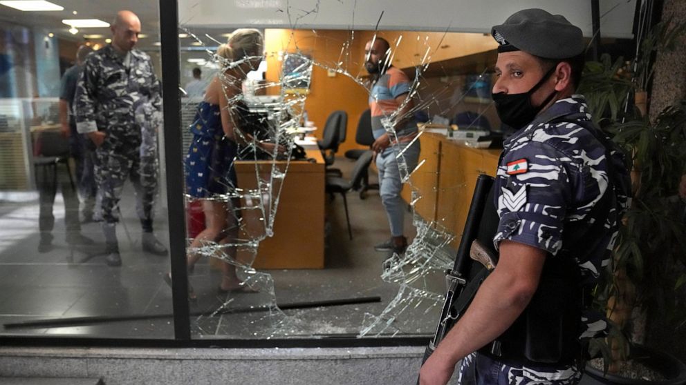 FILE - A Lebanese policeman stands guard next to a bank window that was broken by depositors to exit the bank after attacking it trying to get blocked money, in Beirut, Lebanon, Wednesday, Sept. 14, 2022. A Lebanese activist group said they will cont