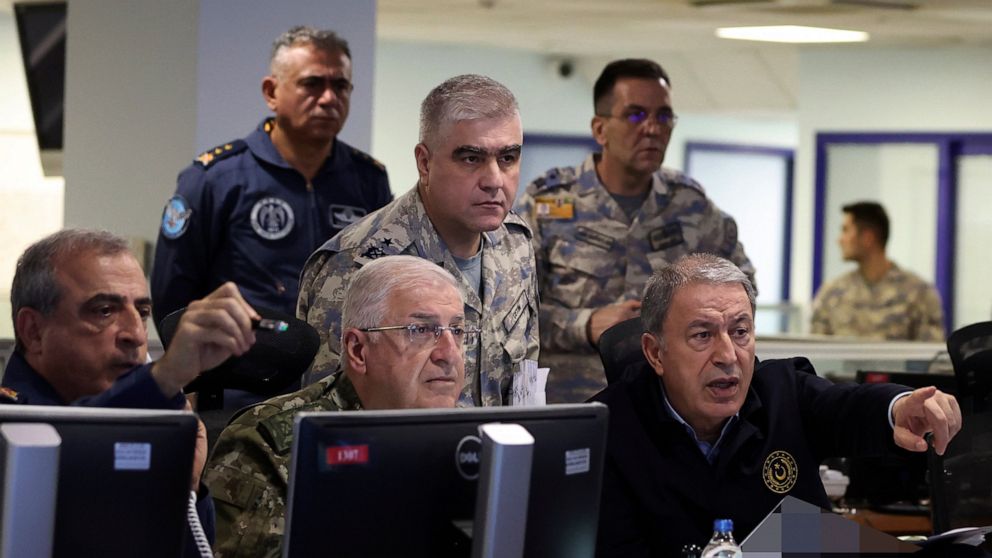 In this photo released by Turkey's defense ministry, Defense Minister Hulusi Akar, right, and top army commanders work at the Air Force command center, in Ankara, Turkey, early Sunday, Nov. 20, 2022. Turkey launched airstrikes over northern regions o