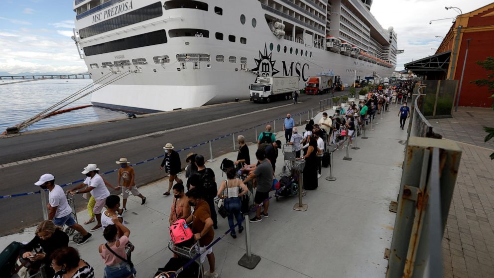 Passengers disembark from the cruise ship 'MSC Preziosa'', in the Port Area of Rio de Janeiro, Brazil, Sunday, Jan. 2, 2022, after Brazil's Sanitary Agency has confirmed more cases of COVID-19 on board. Rio's Health Secretariat said that those living